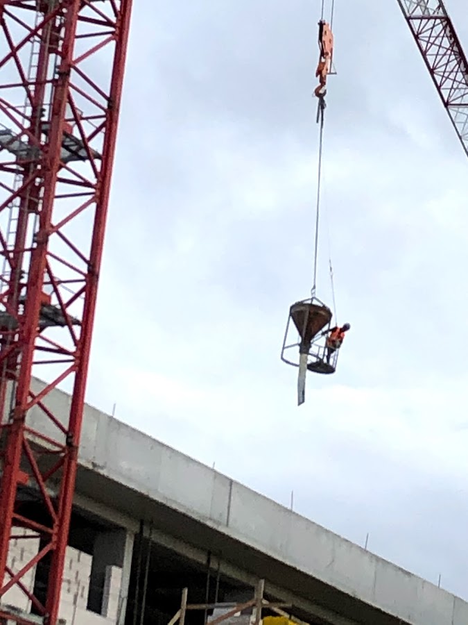 A cement bucket in use with a ride on position for the transport of workers. 